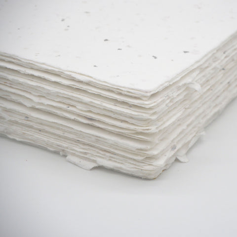 A stack of white deckle edge hand made paper embedded with silver leaf