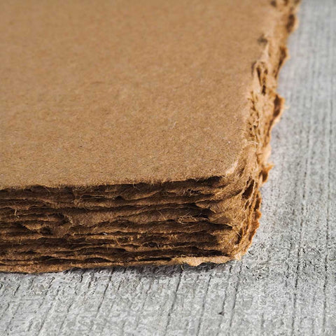 A stack of warm brown deckle edge hand made paper made from recycled cardboard