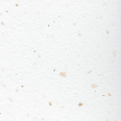 A closeup of white deckle edge hand made paper embedded with gold leaf