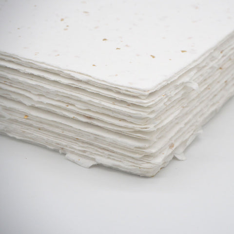A stack of white deckle edge hand made paper embedded with gold leaf
