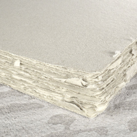 A stack of warm grey deckle edge hand made paper