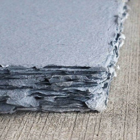 A stack of dusty blue deckle edge hand made paper made with recycled denim