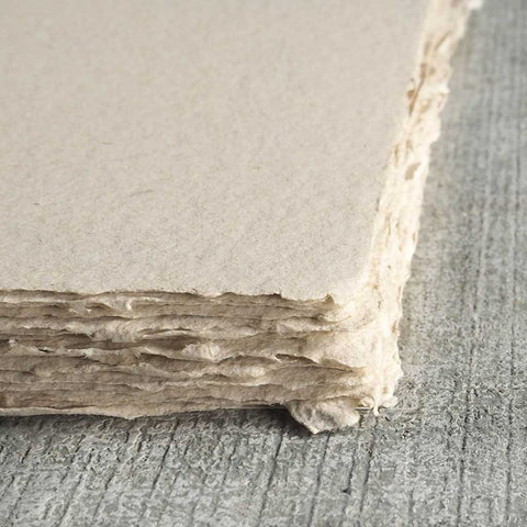 A stack of light sandy brown deckle edge hand made paper made with cotton and recycled chipboard