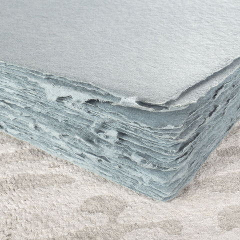 A stack of dusty blue deckle edge hand made paper