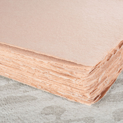 A stack of dusty warm pink deckle edge hand made paper