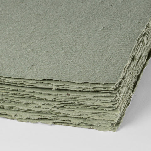 A stack of natural green deckle edge hand made paper embedded with wildflower seeds