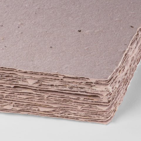 A stack of dusty lavender deckle edge hand made paper embedded with wildflower seeds