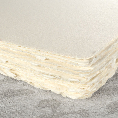 A stack of creamy off-white deckle edge hand made paper